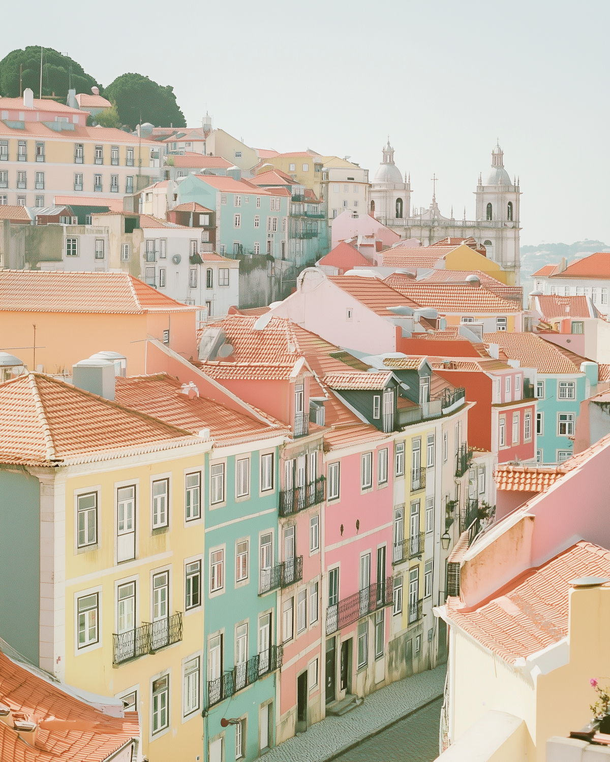 Pastel-painted buildings with terracotta roof tiles stacked along a European street, a historic church tower rising behind them